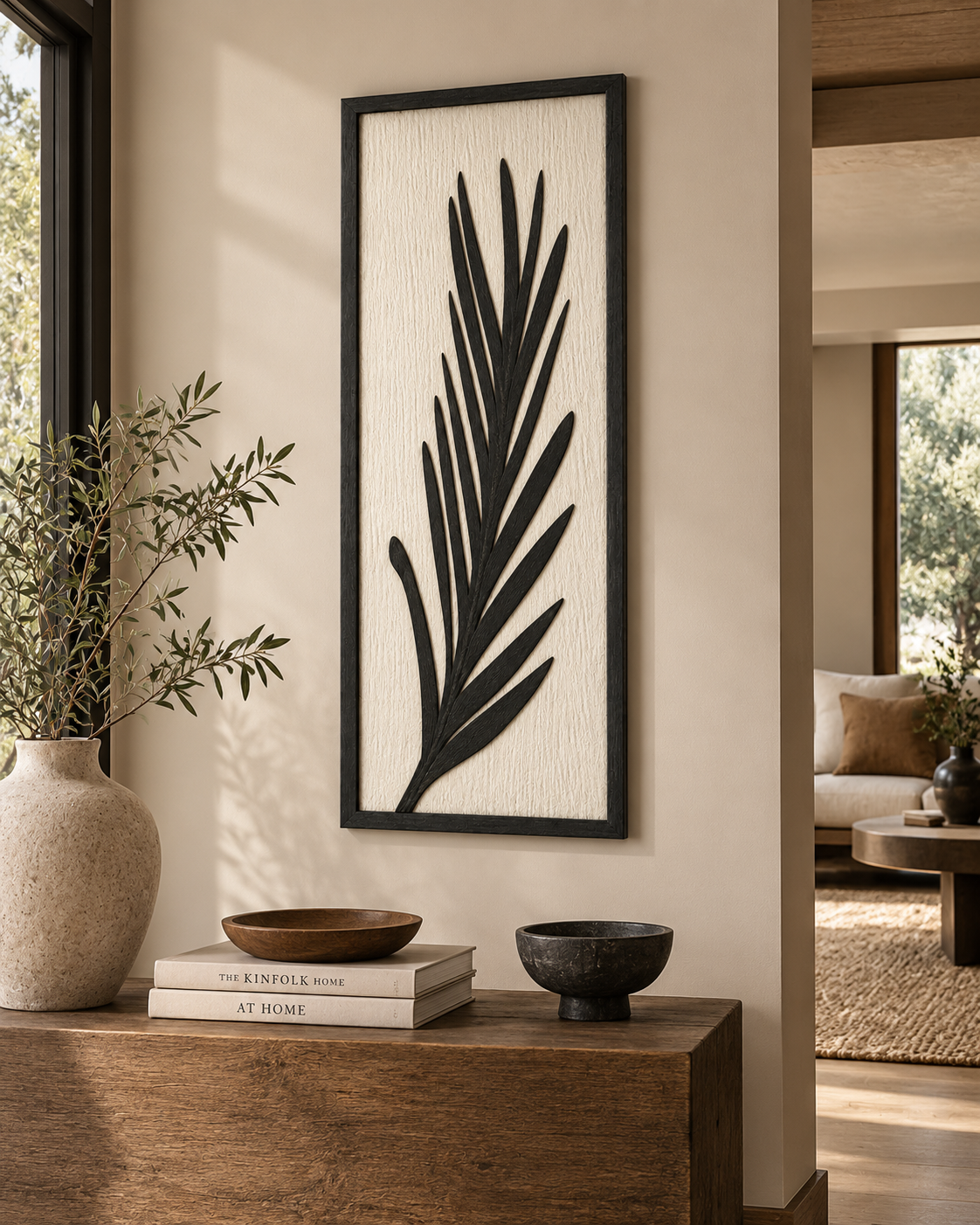 Tall framed wall panel from Kenya with a black frond silhouette on a pale textured ground, hung above a timber console