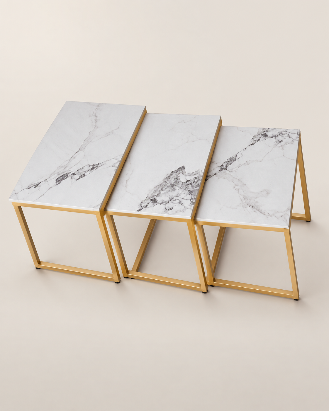 Three nesting side tables from Kenya with slim gold-toned frames and pale grey-veined tops, arranged in a row on a cream backdrop