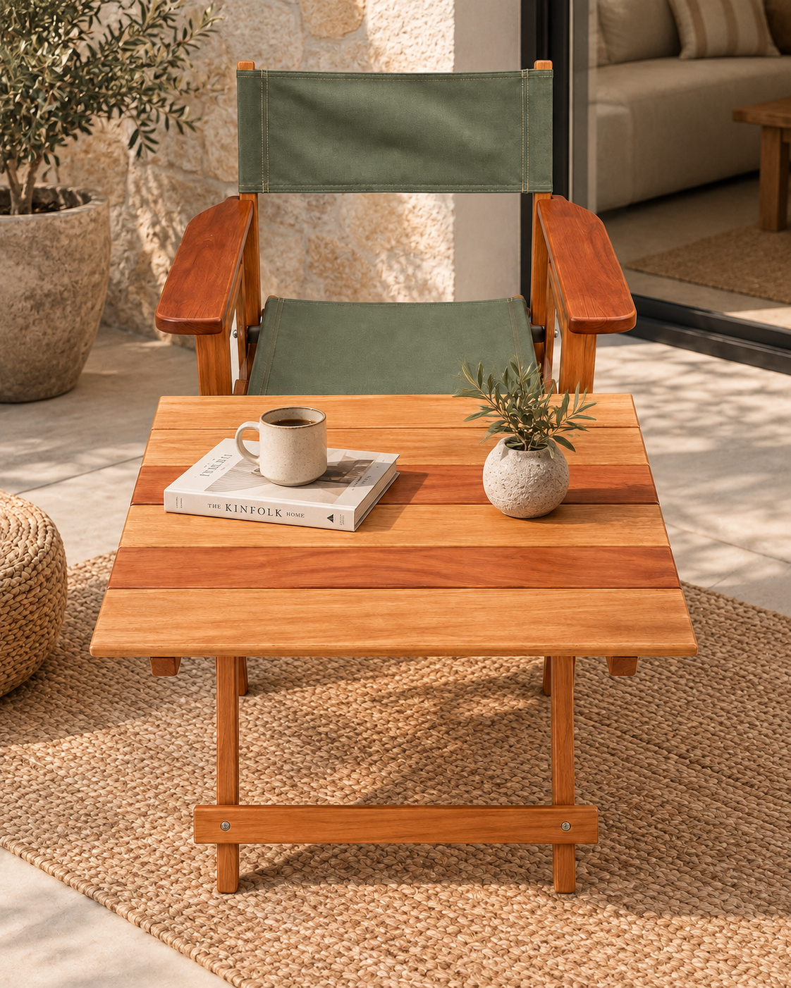Mahogany folding outdoor chair from Kenya with olive-green canvas seat and back, on a woven rug behind a slatted table